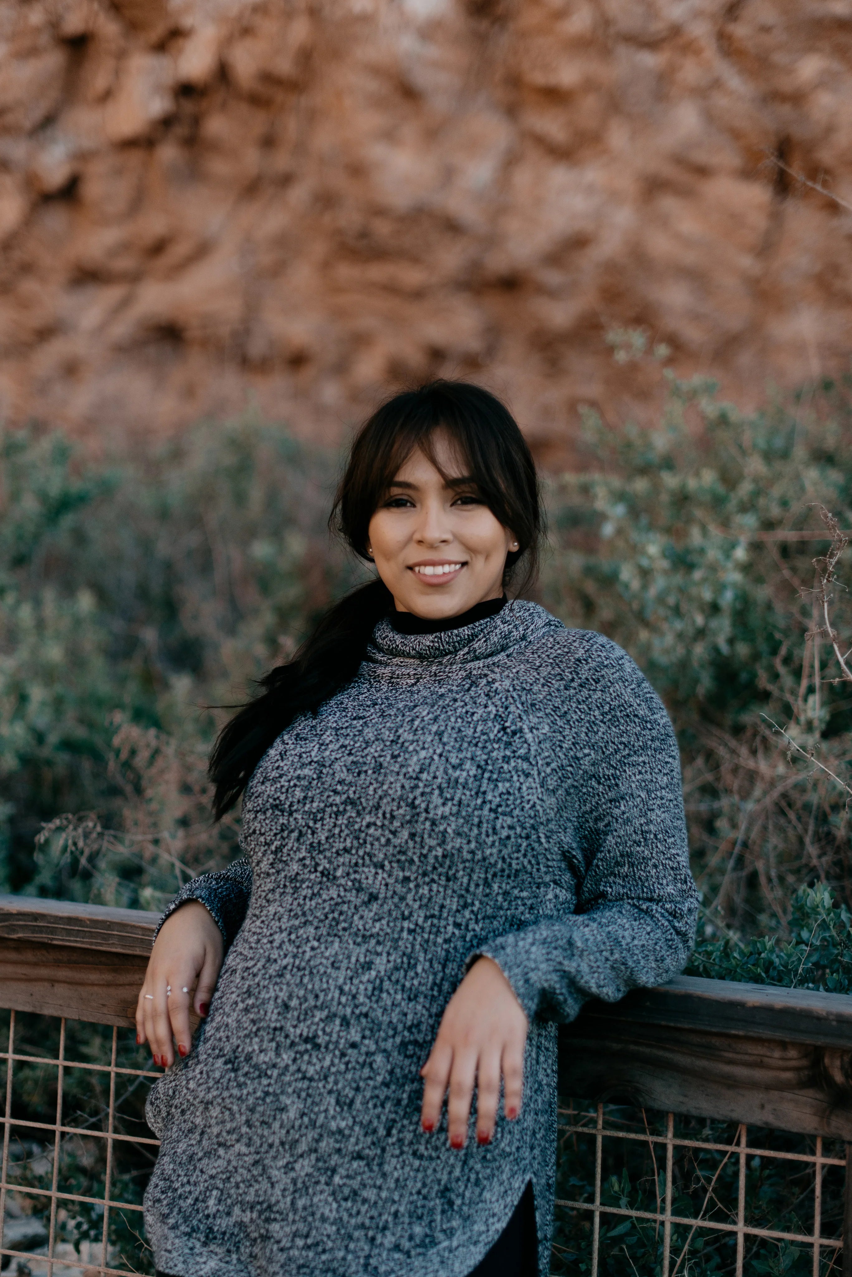 files/woman-in-grey-sweater-smiles-and-leans-against-a-railing.webp